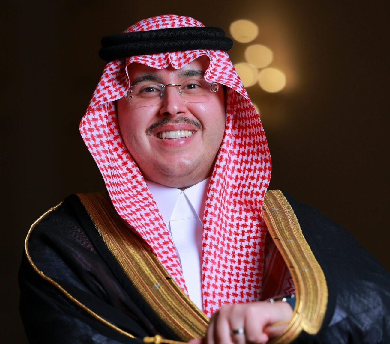 A smiling man in traditional Saudi clothing, embodying cultural elegance and celebration.